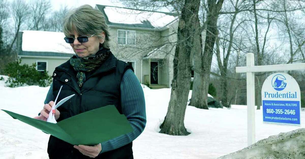 SPECTRUM/Realtor Andrea Swiedler leafs through her information in front of a recwntly sold home on Forest Drive in New Milford. Feb. 17, 2011.