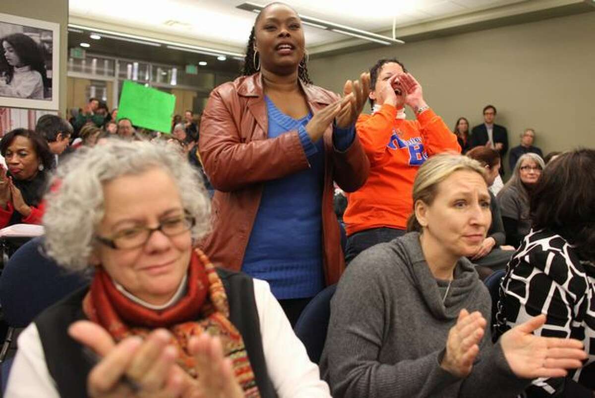 Lacretiah Claytor, center, and Carlina Brown, in orange, cheer as Director Betty Patu addresses the public during a meeting of the Seattle Public School Board of Directors.