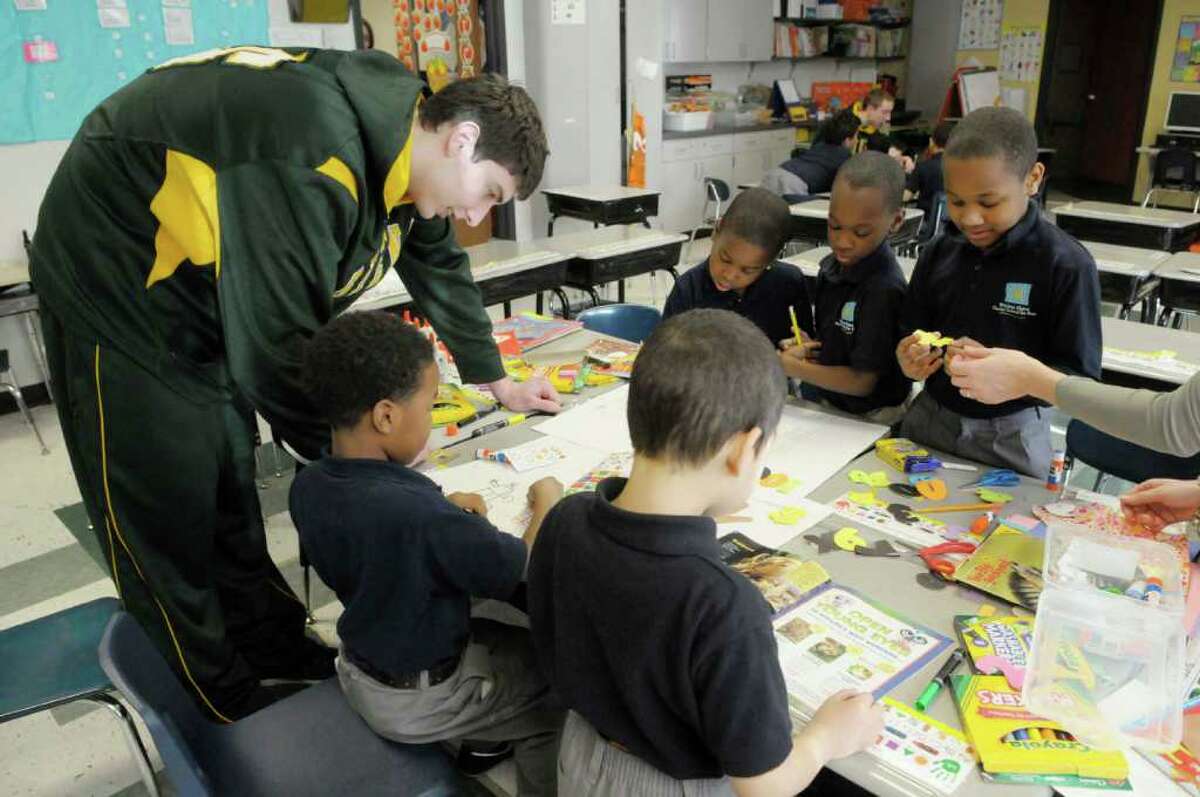 Siena basketball player, Ryan Rossiter, left, works with first graders on an art project at Brighter Choice Charter School in Albany, NY on Wednesday, Jan. 5, 2011. Three players and one assistant coach from Siena came to the school to answer questions posed by students and to work with first graders in different activities. (Paul Buckowski / Times Union)