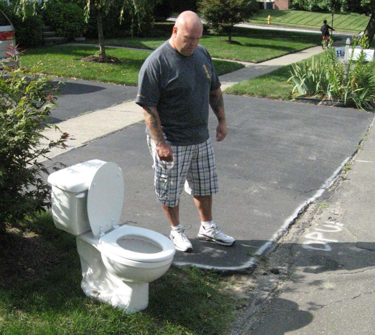 Grant Dalling of 385 Bunnyview Drive, Stratford, looks at snowplow damage to his driveway that the town has yet to repair. The toilet is his message of silent protest to Stratford officials.