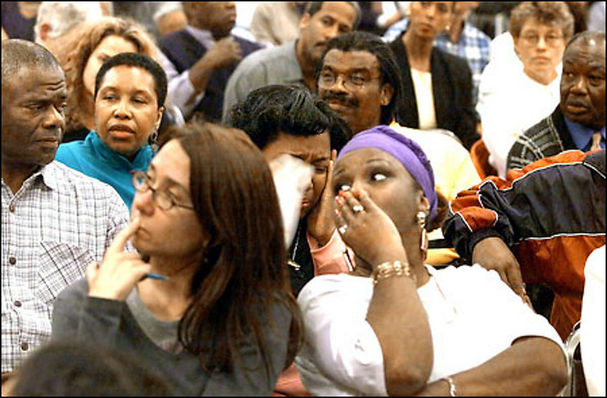 Michelle Dent, left, and Catheryn Elder listen to speakers address the police chief and mayor about issues in the black community. Behind them is a woman who identified herself as Nancy, a property owner in the Central Area who believes that "the cops are hunting down black men," and that her husband is in danger.