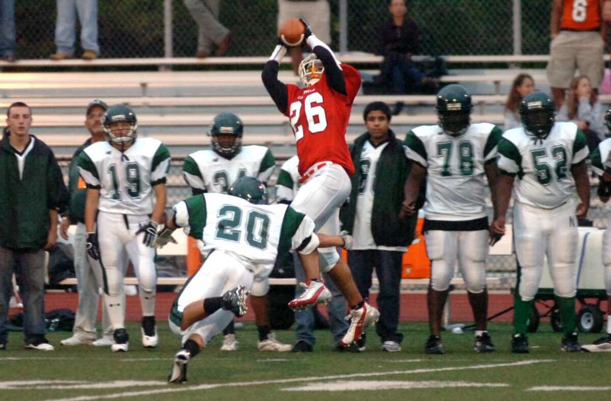 Greenwich Cardinal Camryn Ferrara receives as Norwalk Bear Marc Lugo moves in to defend during second period action. Greenwich High School meets Norwalk High School at Greenwich Cardinal Stadium for Greenwich football home opener Tuesday evening, Sept. 16, 2009.