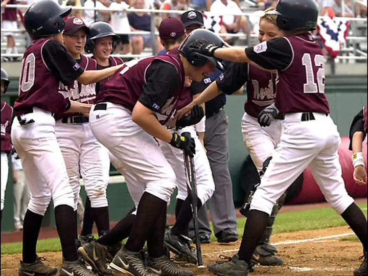 Coby Gibler ducks as Bainbridge Island players surround him after his winning homer against Davenport on Saturday.