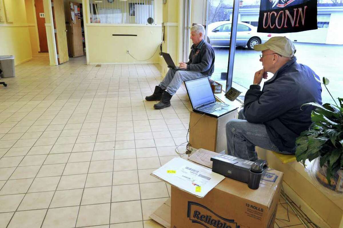 Jim Williams, right, owner of Southworth Sales & Service on Route 7 in New Milford, and Phil Buxbaum, general manager, work on laptop computers in their empty showroom. Southworth moved its cars and furniture, computers and other office content out of the building in anticipation of possible fllooding. Heavy rain is expected Friday. Photo taken Thursday, March 11, 2011.