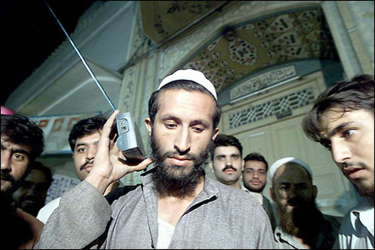 Pakistanis listen to a radio for the latest developments in a shop in downtown Peshawar. Many in the Muslim country are sympathetic to the Taliban cause.
