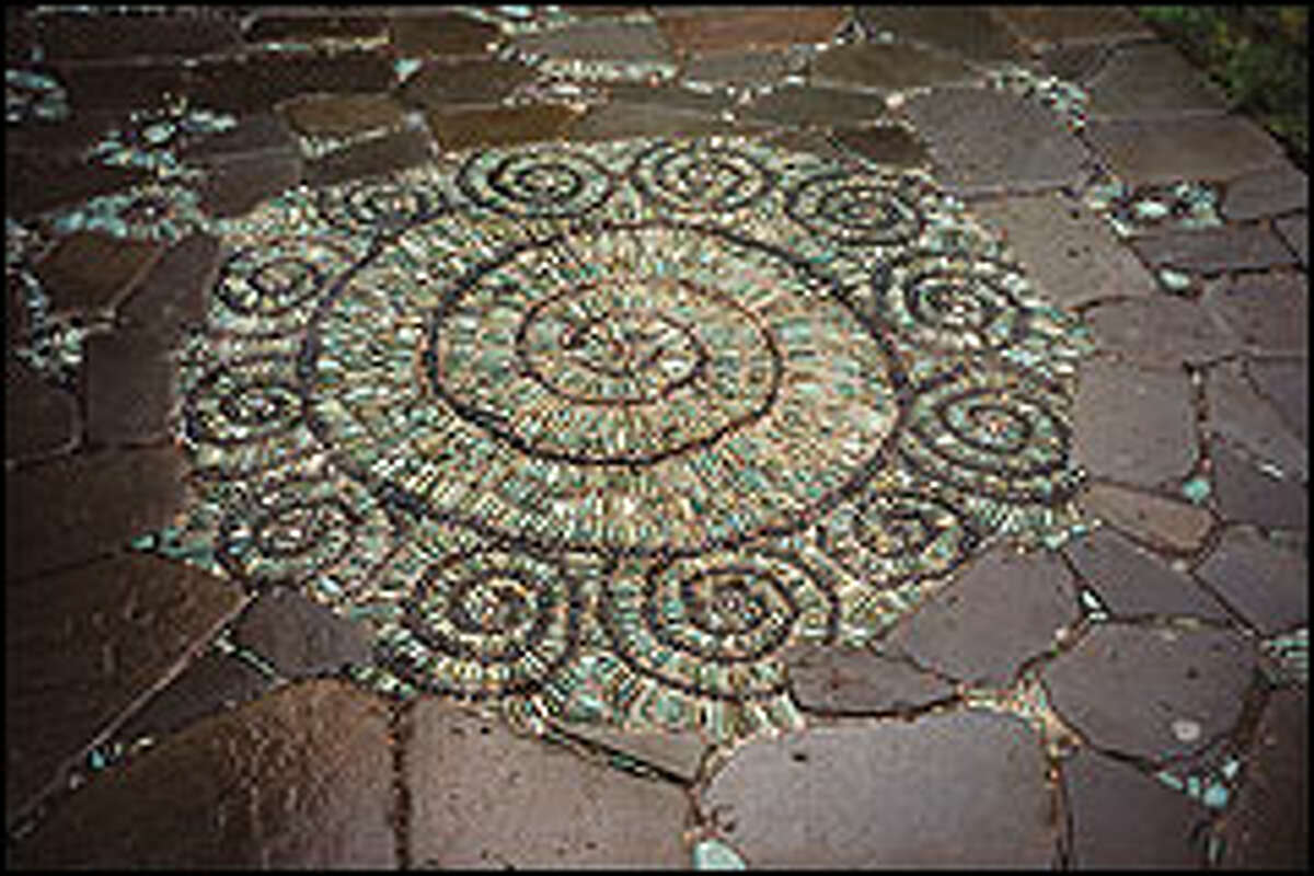 A spiral mosaic set in a green tumbled sandstone patio has 12 small spirals surrounding it that represent the full moons of the year, Bale says. The patio is studded with thousands of iridescent glass marbles.