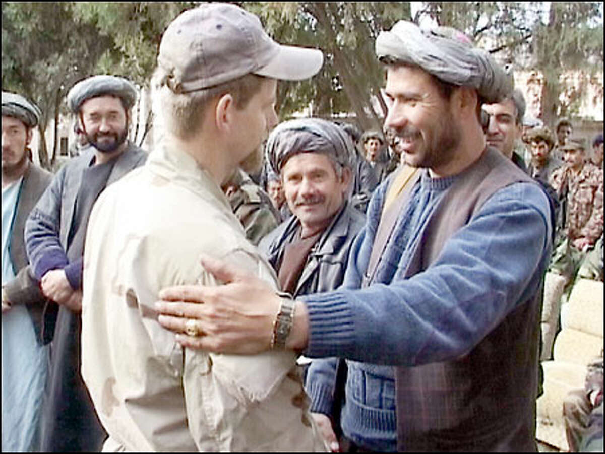 An American officer identified only as Captain Mark, left, shakes hands with an Afghan commander at a ceremony yesterday.