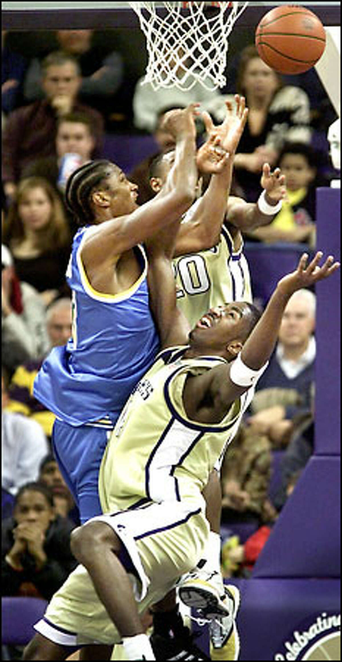 UCLA's T.J. Cummings has the ball knocked away on a drive against the Huskies' Curtis Allen (20) and Jeffrey Day.