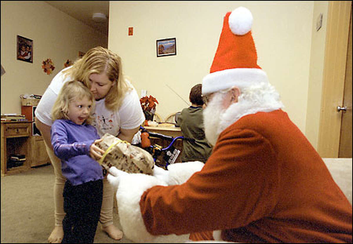 Elisa McCoy reacts to a present given to her by Santa. With her is her mother, Angela McCoy, and Jacob, her brother.