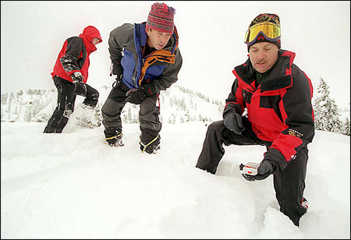 Avalanche safety expert Gary Brill, center, looks at the reading on KING-5 weather expert Jeff Renner's transceiver during a class on how to find an avalanche victim.
