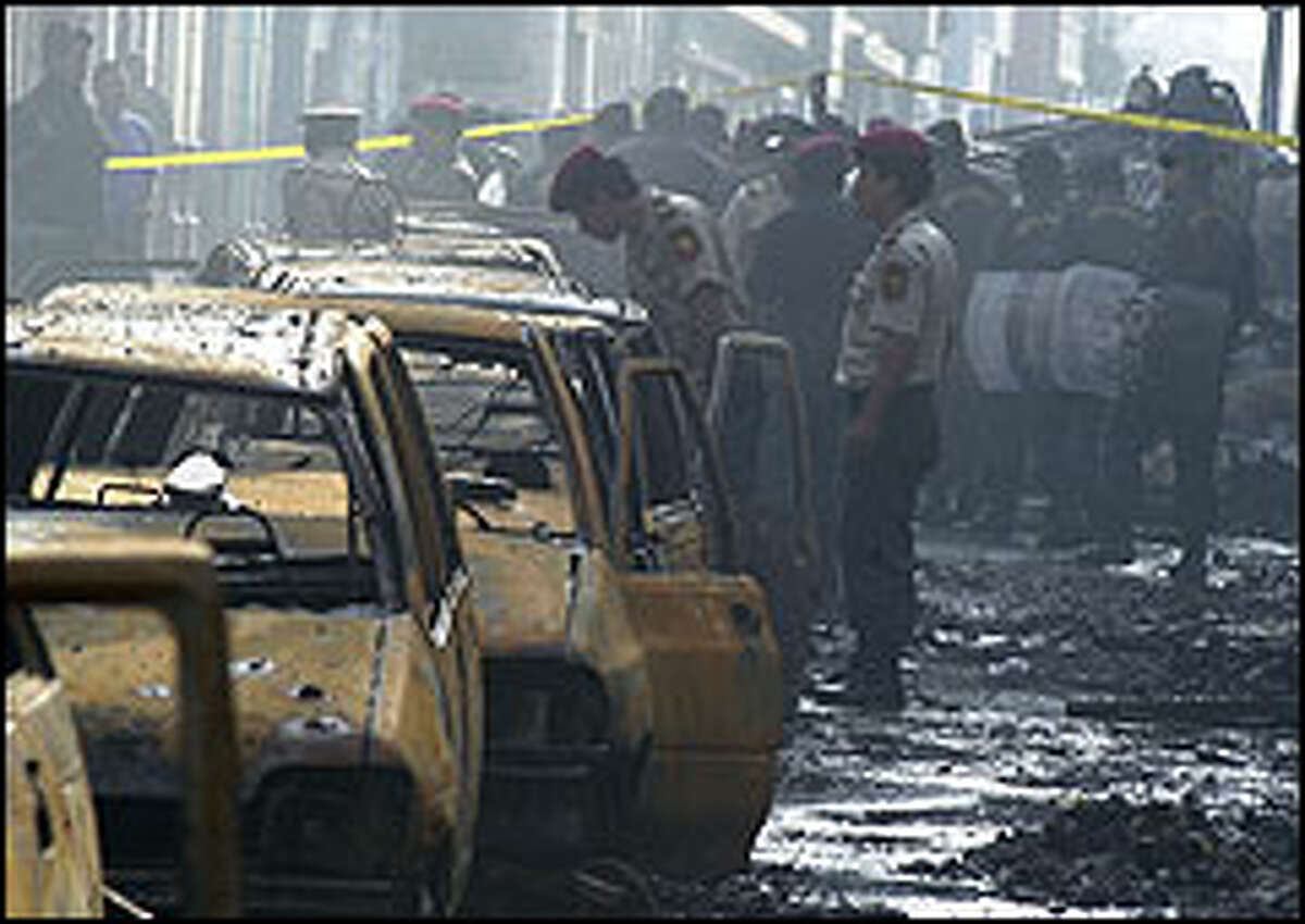 Police check destroyed cars after a fireworks-fed conflagration killed hundreds in Lima, Peru. Many were trapped in shops, cars and apartments.