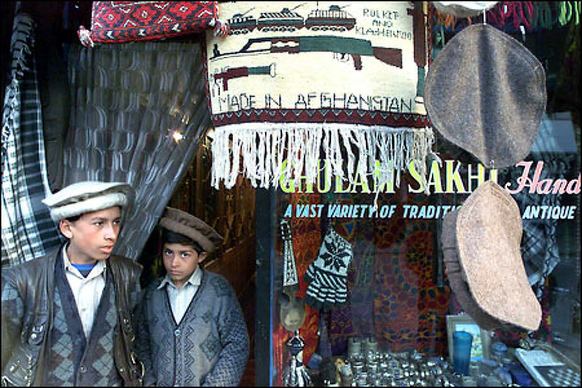 Two Afghan boys wait for customers at the entrance of their father's shop, which sells souvenirs, antiques and handicrafts in downtown Kabul.
