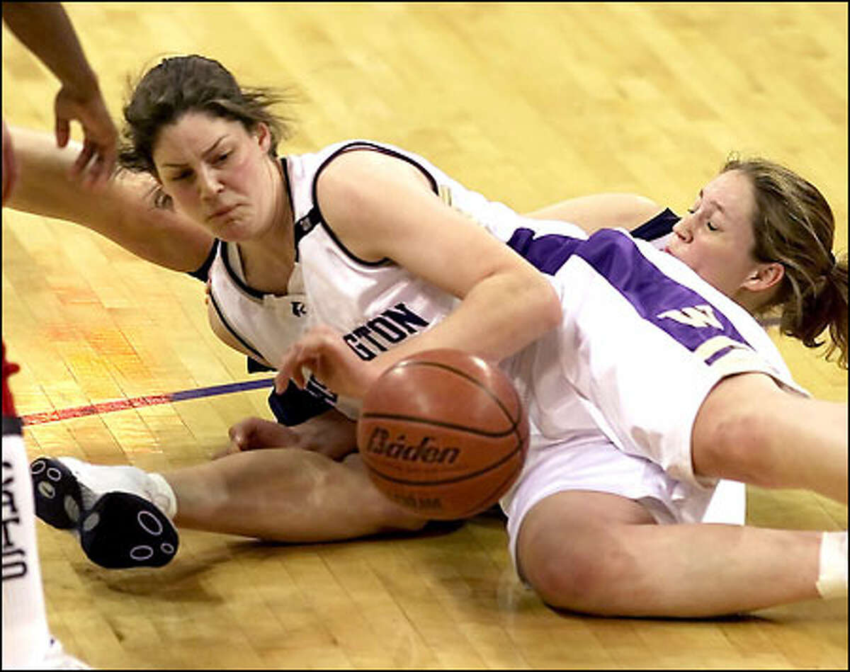 Kirsten Brockman crashes into Arizona’s Julie Brase and recovers the ball. The Huskies won their fourth game in a row, 77-73.
