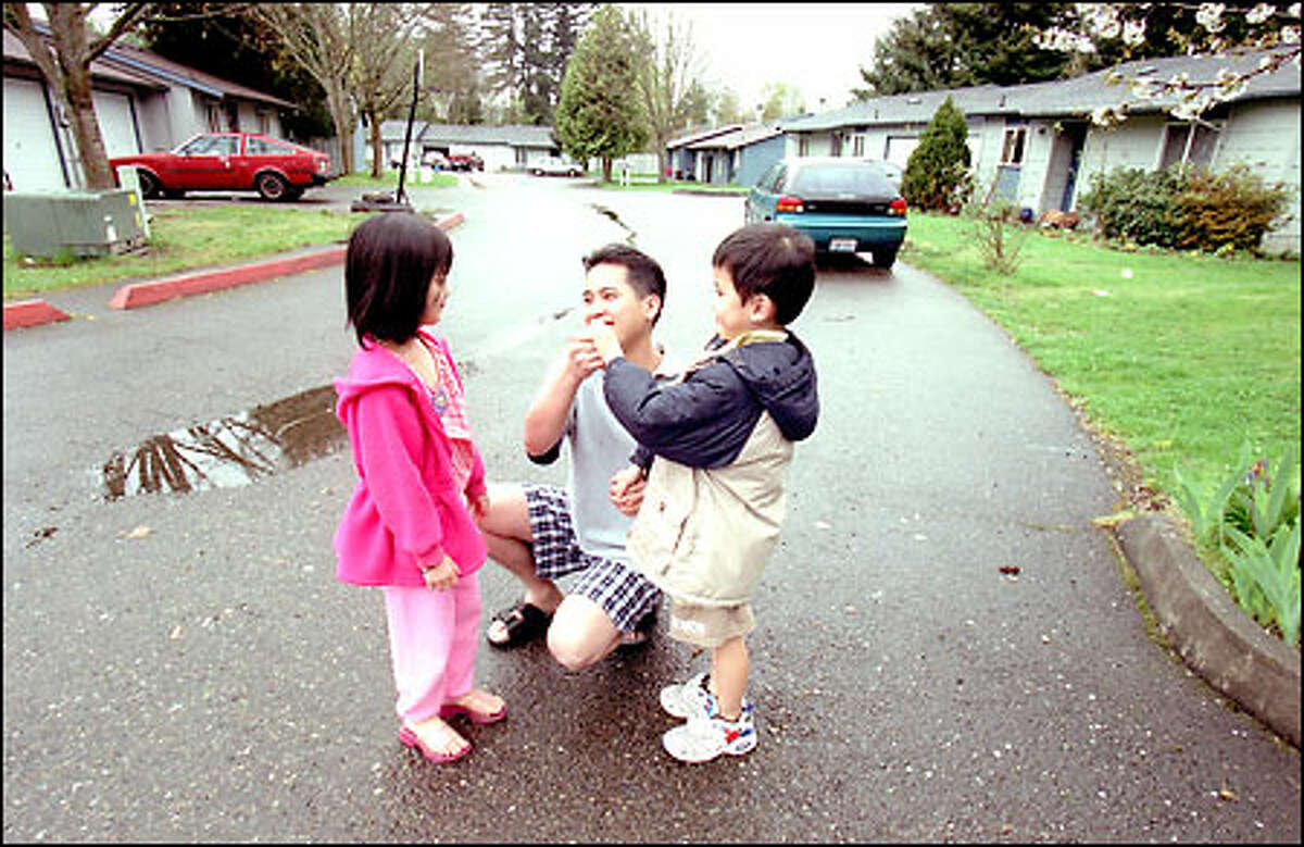 Puan Tran talks with his children, Terri, 6, and David, 5, recently near their home in Benson East on Southeast 223rd Place in Kent. The Benson East residents banded together to buy their entire neighborhood.