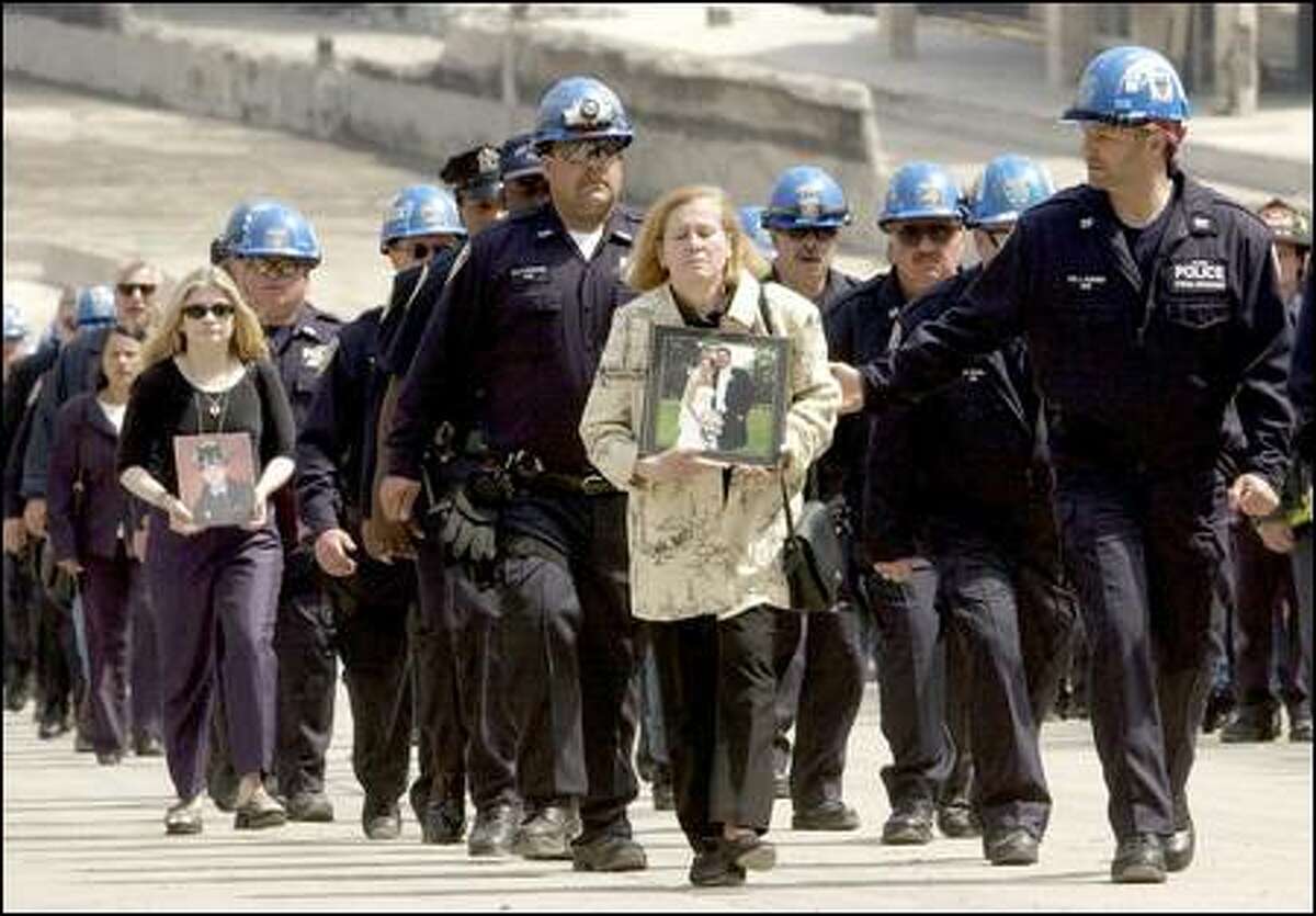 Authority Police march from ground zero with Maria Sanpio, right, and Christina Regenhard, second from left, holding photos of family members who died.