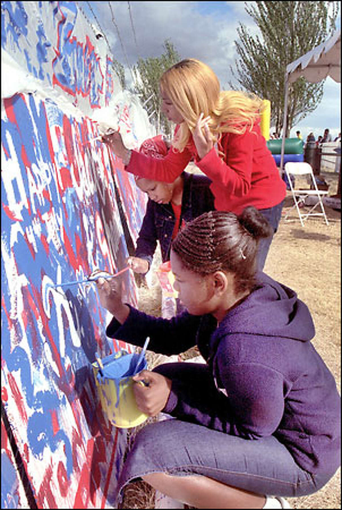Shanae Kimble, front, and sisters Jacobie and Kem Davis paint messages on boards before the fireworks display at Myrtle Edwards Park.