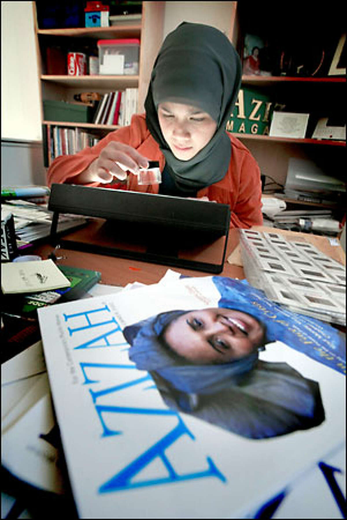 Marlina Soerakoesoemah, creative director for Azizah magazine, edits fashions pictures for the magazine in her Redmond home office. "You still hear horrible stories about (Muslim and Arab) people being profiled and harassed," she says.