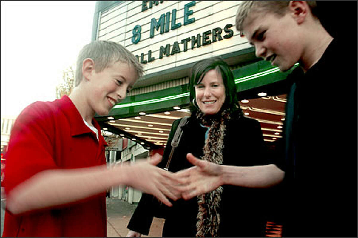 Evan Lince, 13, left, and Kevin Vlcek, 13, demonstrate a handshake they saw in "8-Mile." Watching is Janet Leduc, who took the boys to see the R-rated film. The movie could "breed some understanding of rap," Leduc said.