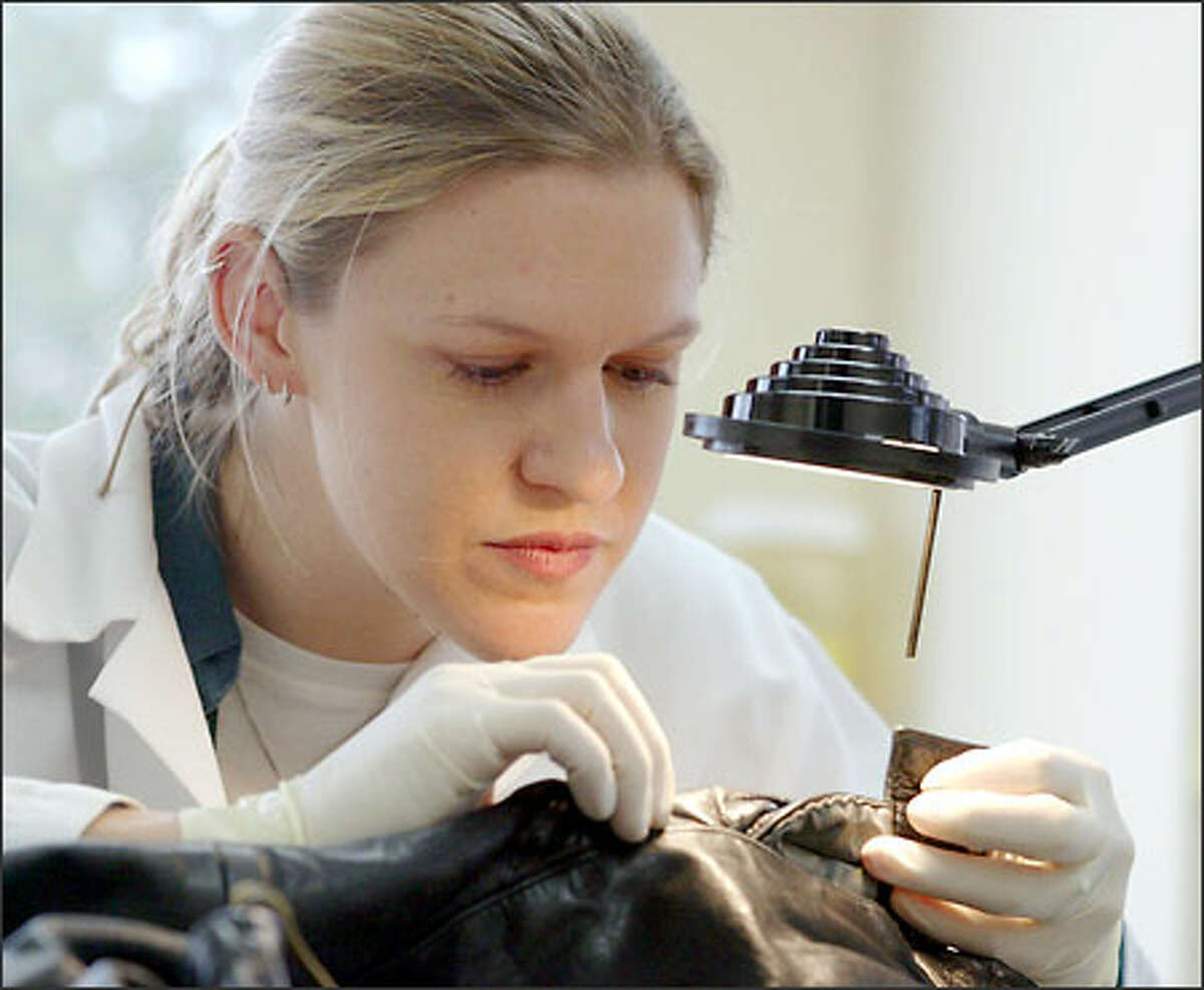 Katie Woodard, a forensic scientist at the Washington State Patrol Crime Lab, examines a coat for blood spatters. When found, she removes it for DNA analysis.