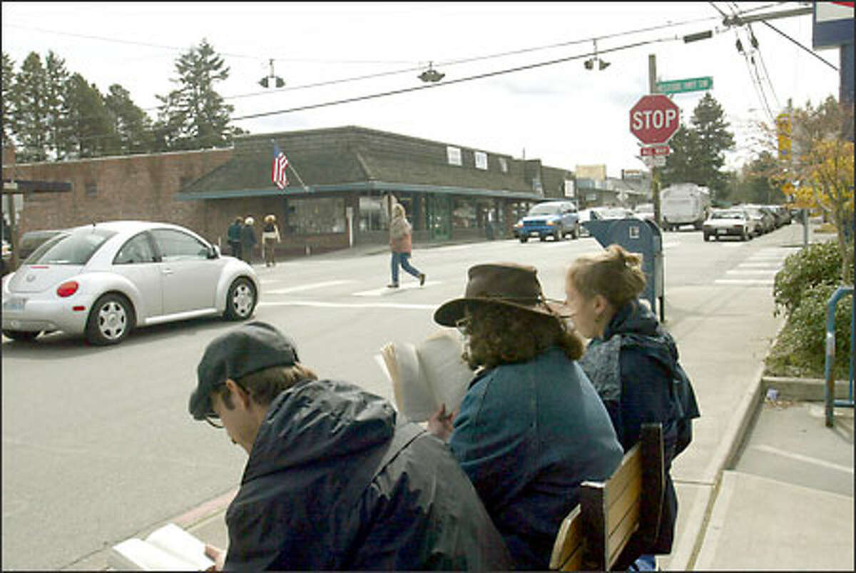Jefferson Vann, left, Rachel Burnett, and Celina Yarkin wait for a bus near a stop sign at the intersection of Vashon Highway and Banks Road.