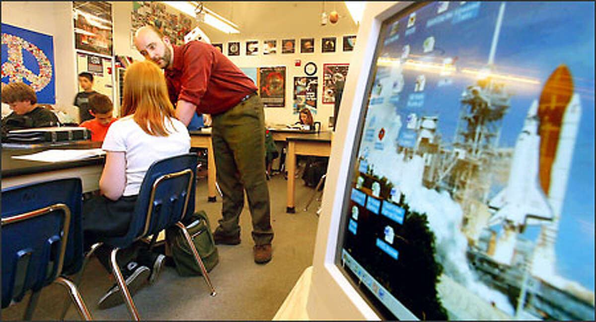 An image of a Columbia space shuttle launch serves as the screensaver on a classroom computer as teacher Alex Koerger helps a student at the Brighton School in Lynnwood.