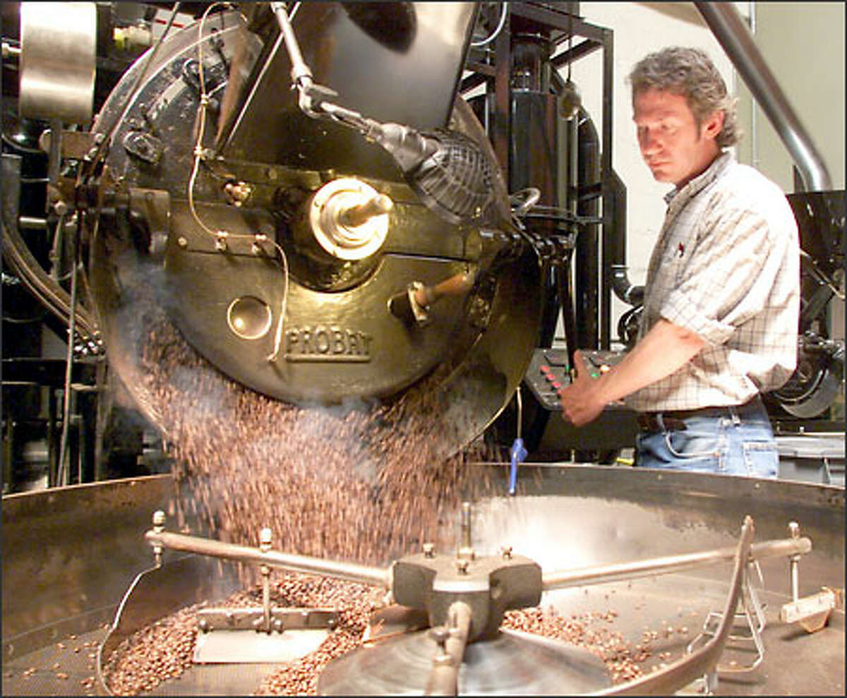 Dan Donahue, head roaster at Cafe Vita, releases the roasted coffee beans into a bin, where they are cooled before being packed for shipment.