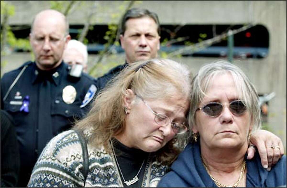 Antoinette Bunch, left, and Nancy Bertucci, who said they are both victims of domestic violence, mourn for Crystal Brame at a memorial service held at Theatre Square Park in Tacoma Friday. Tacoma Police public information officer Jim Mattheis, left, and acting police chief Donald Ramsdell stand in the background.