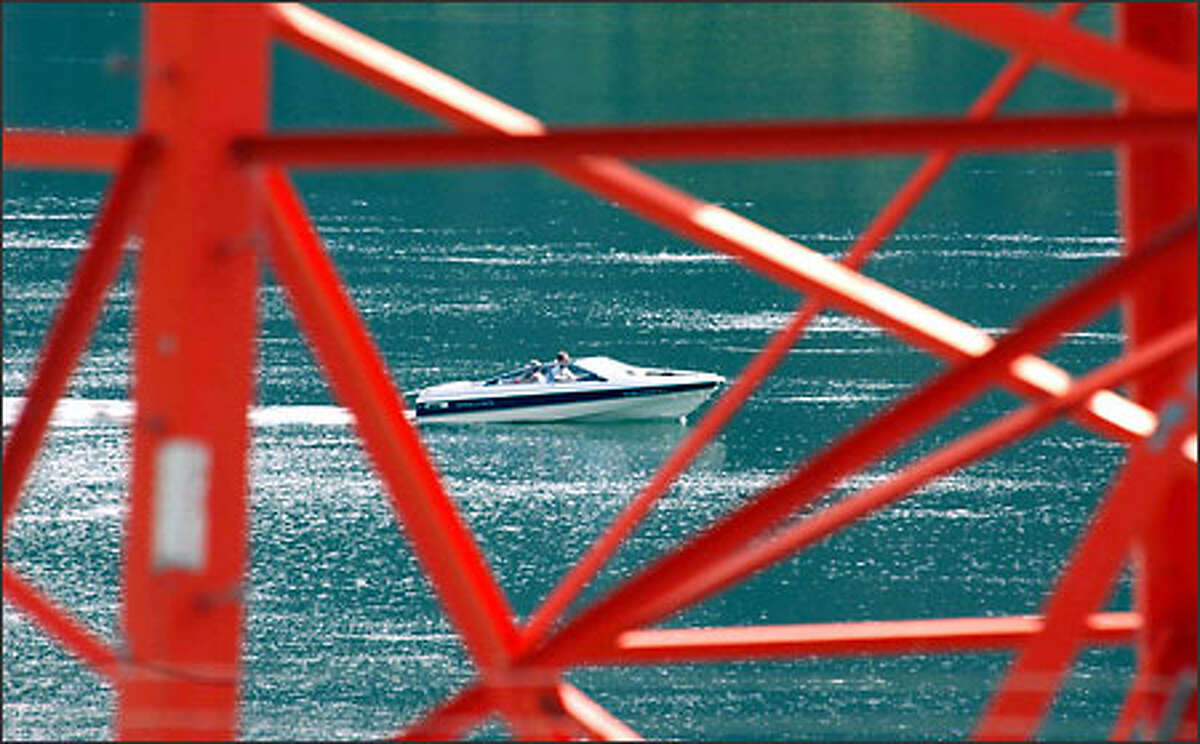 A power boat on Lake Entiat is framed in the struts of a power line support tower at Daroga State Park just south of Chelan.