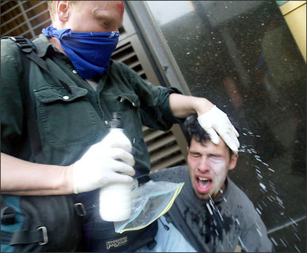 One man washes out the eyes of another after he was sprayed by police.
