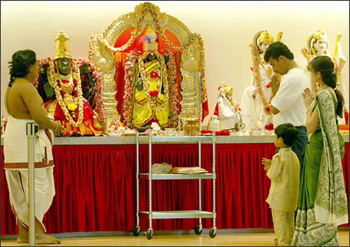 At the Hindu Temple and Cultural Center in Bothell, priest Deekshith, left, leads Krishna and Sunitha Murthy and their son Neeraj, 3, in worship.