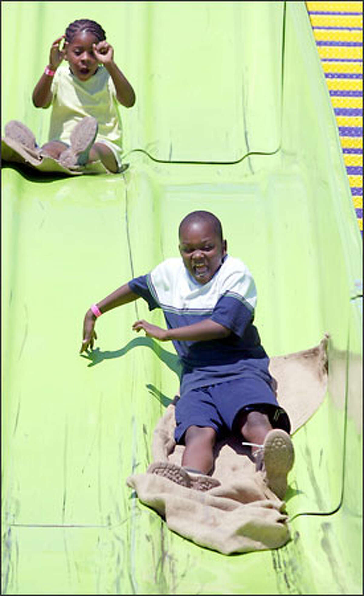 Eight-year-olds Robyn Knott, left, and Jonathan Foster-Knott enjoy a ride on The Super Slide yesterday at Soul Fest. The festival is in its 16th year and continues this weekend at Franklin High School.