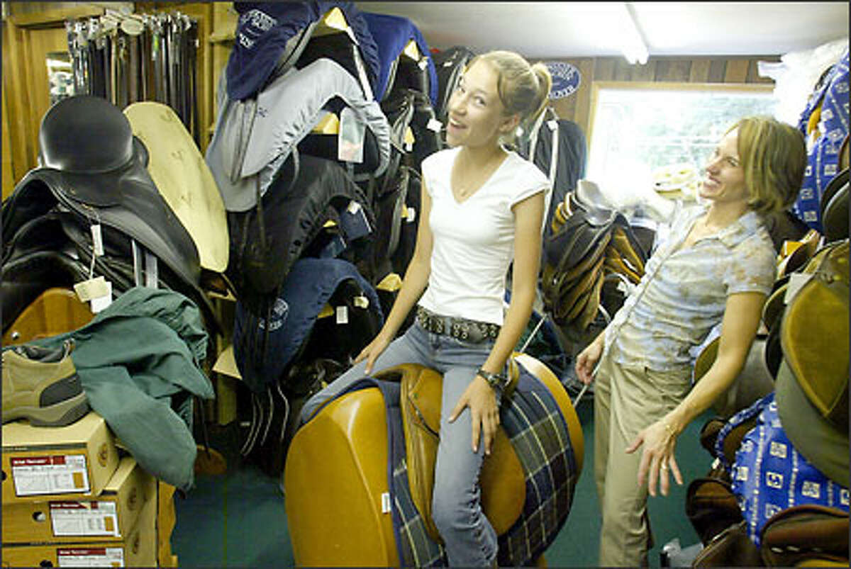 Gabrielle Hansen, left, clowns around with manager Heather Manuel as she tries out a used saddle at Olson's Tack Shop in Bellevue. The business, now catering to English riders, opened in 1945.