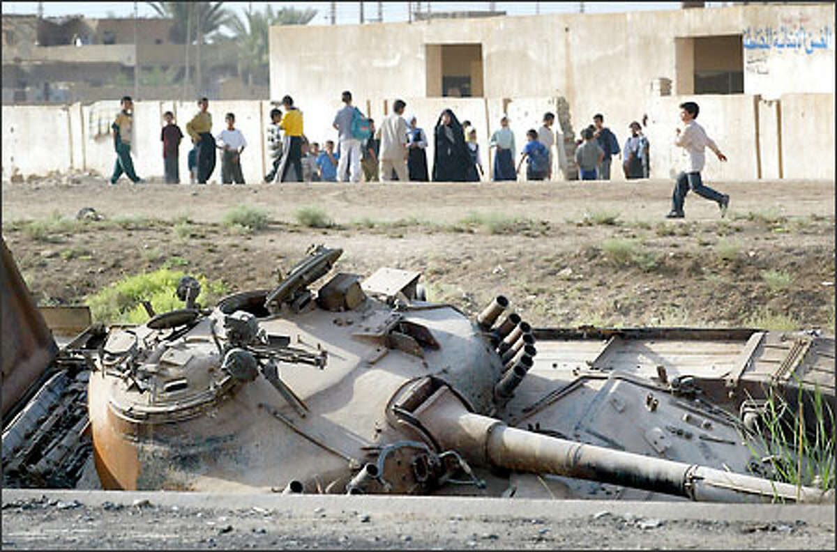 A war-damaged Iraqi tank rests along the highway next to a school on the outskirts of Baghdad. Depleted uranium weapons were used in populated areas in Iraq.