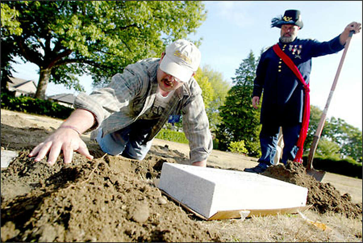 Ken Richmond of the Sons of Union Veterans of the Civil War watches as Rod Fleck replaces a headstone at a cemetery for Civil War vets on Capitol Hill.