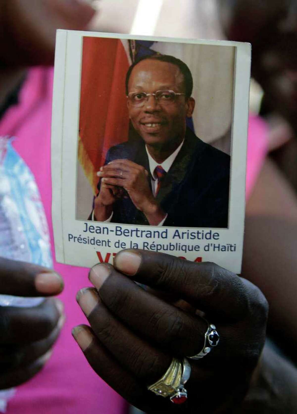 A woman holds a photo of Haiti's ousted President Jean-Bertrand Aristide during in Port-au-Prince, Haiti, Friday, March 11, 2011. Felix said supporters were planning to clean the streets of Port-au-Prince in anticipation of Aristide's return which, according to a South African official, could happen anytime before Haiti's elections next March 20. Aristide is exiled in South Africa since 2004. (AP Photo/Dieu Nalio Chery)