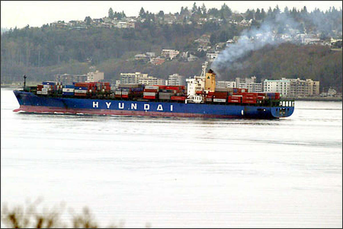 A container ship enters Elliott Bay, with West Seattle in the background. Pollution is likely to get worse as more and faster ships ply the harbor.