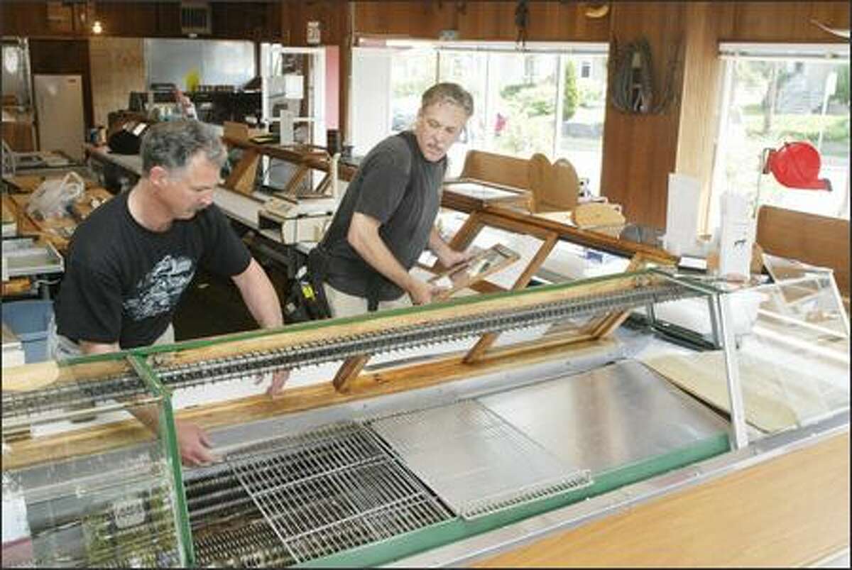 Rick Friar and Dave Friar rearrange counters at A&J Meats on Queen Anne Hill yesterday to make room for Wild Salmon Seafood Market, which is expanding from its Fishermen's Terminal location to A&J. It joins McCarthy & Schiering Wine Merchants at the market, which reopens tomorrow.