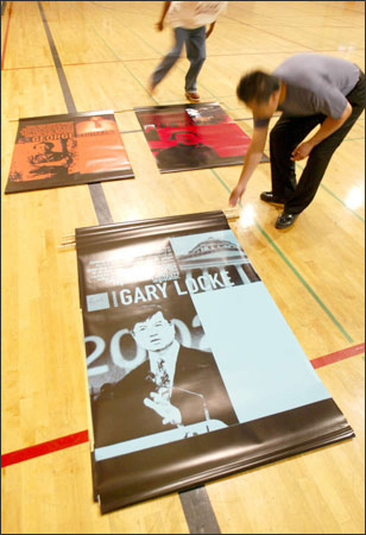 Romel Allen, top, and Jerry Lee, with Mulvanny G2 Architecture, prepare to hang posters of the first five inductees into the Hall of Fame at the Asian Resource Center in Seattle yesterday.