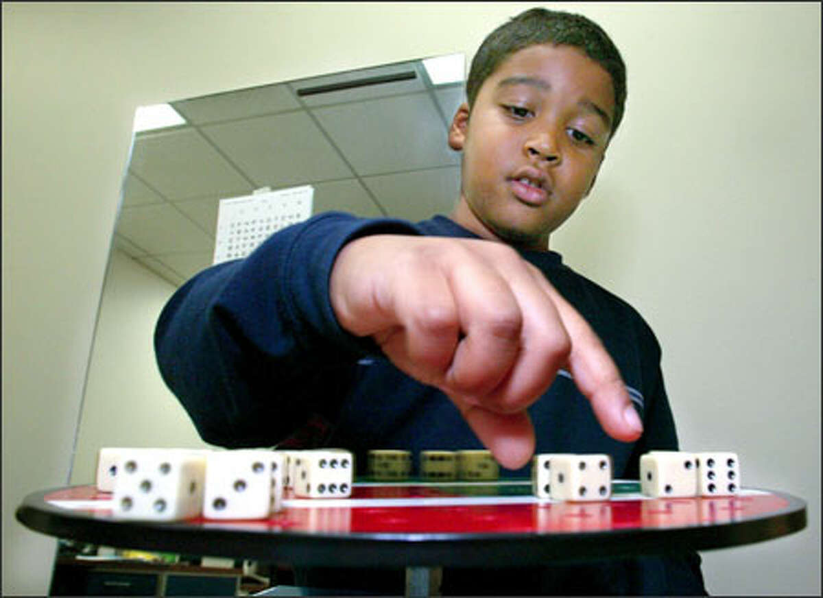 Kumar reaches for a die on a rotating turntable covered with dice. He picks them up in different order. The exercise is designed to assist Kumar to track something while it is in motion.