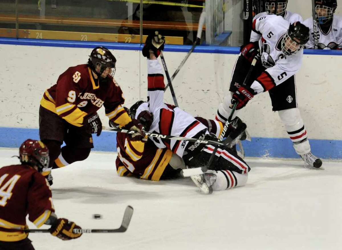New Canaan's #5 Tom Krieger, right, sends the puck through a bottle neck of players, during CIAC Class I semifinal boys hockey action against St. Joe's at Yale's Ingalis Rink in New Haven, Conn. on Wednesday March 16, 2011.