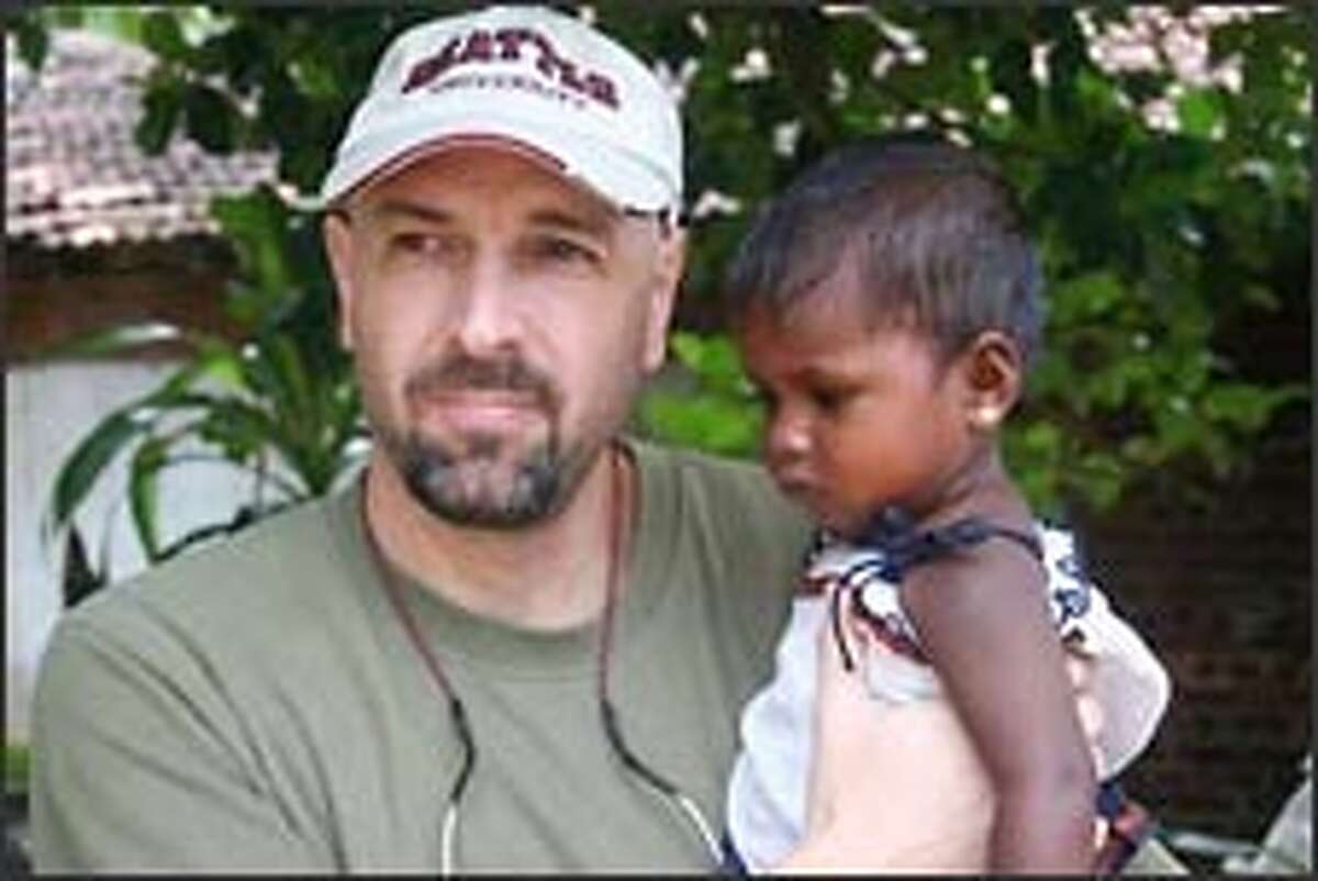 Adam Salmon, shown holding an orphan in Sri Lanka, says, "Every single place I go my heart is ripped out. Then I have to pull out and go to the next place."