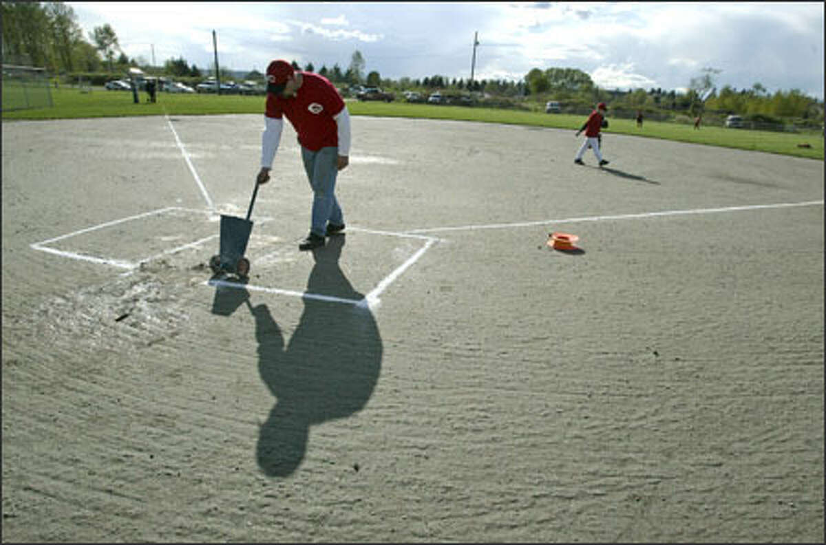 Kurt Lanter, a manager in the North Snohomish Little League, lays down the lines for the batting box before a game yesterday at a field built illegally on farmland near Snohomish.