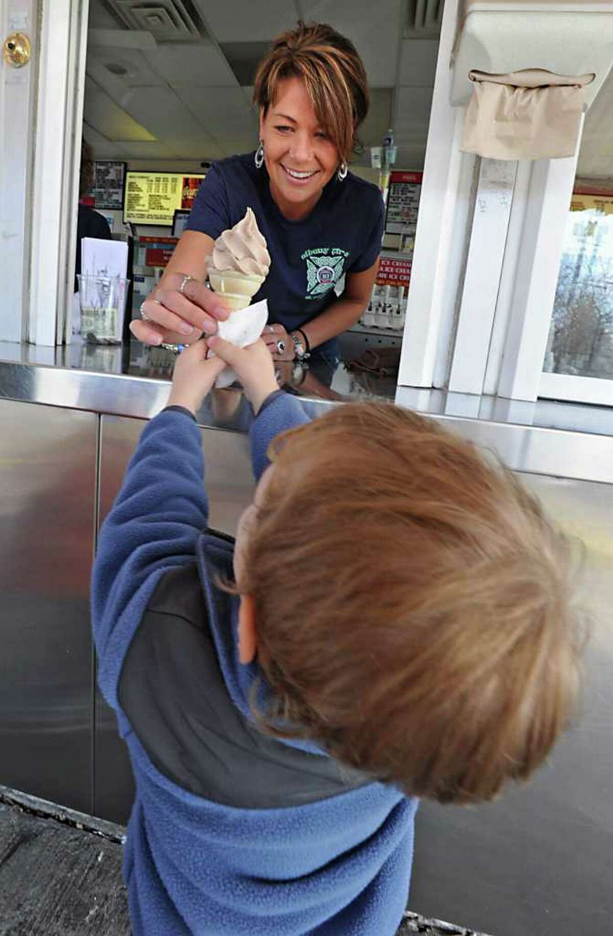 Cheryl McCarroll, daughter of Kurver Kreme owner Lorie Meineker, hands an ice cream cone to customer Robbie Frey, 3, of Colonie, on opening day of the season in Colonie, NY, on March 17, 2011. (Lori Van Buren / Times Union)