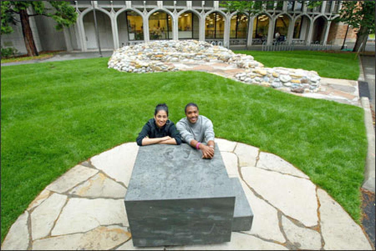 Sumona Das Gupta, left, and Jaebadiah Gardner lean on the slave auction block of their sculpture "Blocked Out," which honors those who are oppressed. Hear Gupta explain what the sculpture represents.