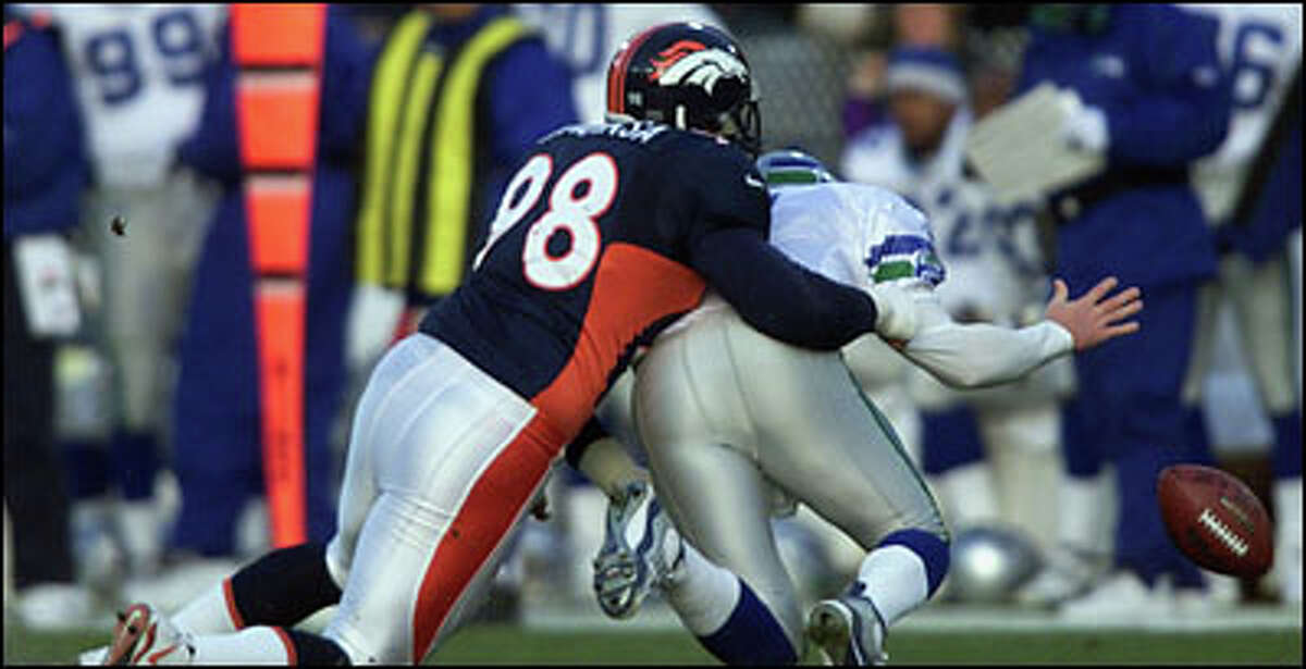 Seahawks quarterback Jon Kitna fumbles the ball while being sacked by Broncos' Maa Tanuvasa. The Broncos recovered the ball.
