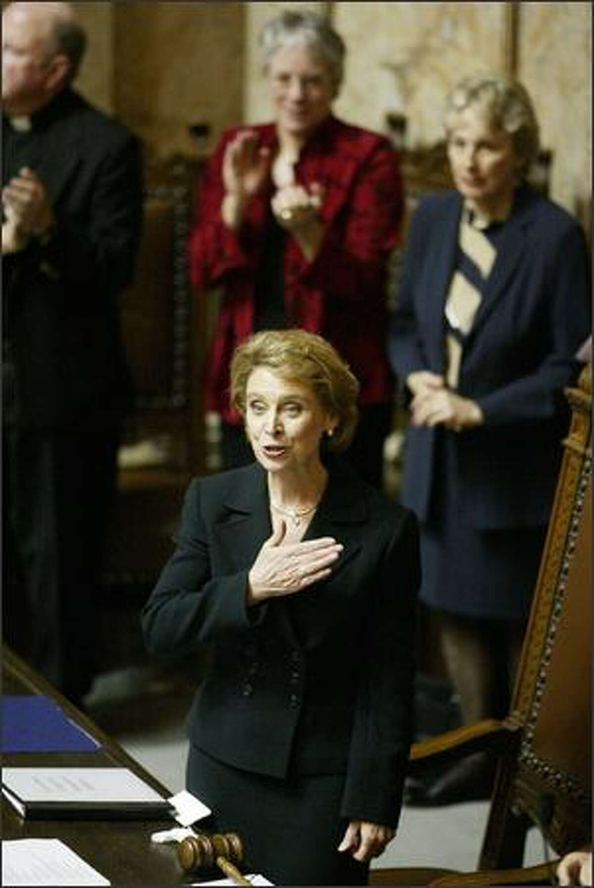 With a hand placed over her heart, Christine Gregoire acknowledges her family sitting in the gallery after she is sworn in as governor in the Legislature.