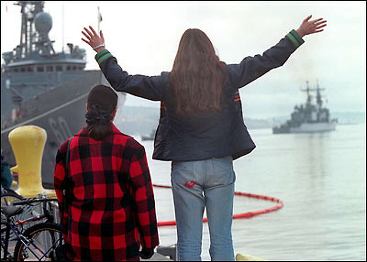 Ginger Lawrence, 19, waves goodbye to friend Adam Bruce Sinclair, 19, as he leaves aboard the USS Paul F. Foster, at right, for a six-month deployment to the Persian Gulf. Ginger’s mom, Rita, left, said: "It's sad to see such young, beautiful and focused people leave."