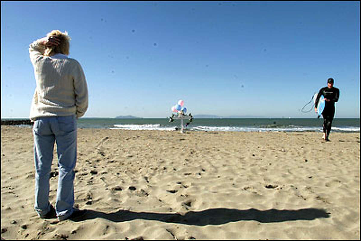 Nancy Fry looks at the memorial cross she set up at Silver Strand Beach in Oxnard, Calif., to honor those who died when Alaska Flight 261 crashed off Anacapa Island, in the backround, on Jan. 31, 2000. Last year Fry put up the first cross, which became the focal point for personal memorials placed by relatives and friends of the crash victims.
