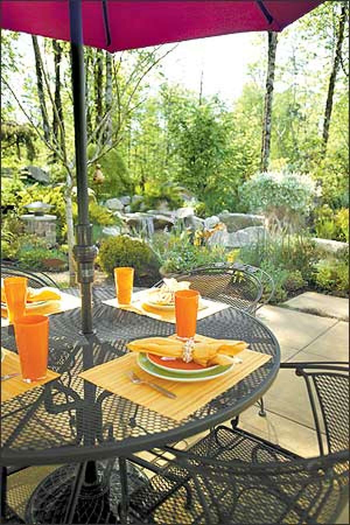 An umbrella-topped wrought-iron dining set allows guests to choose between eating in the sun or shade.