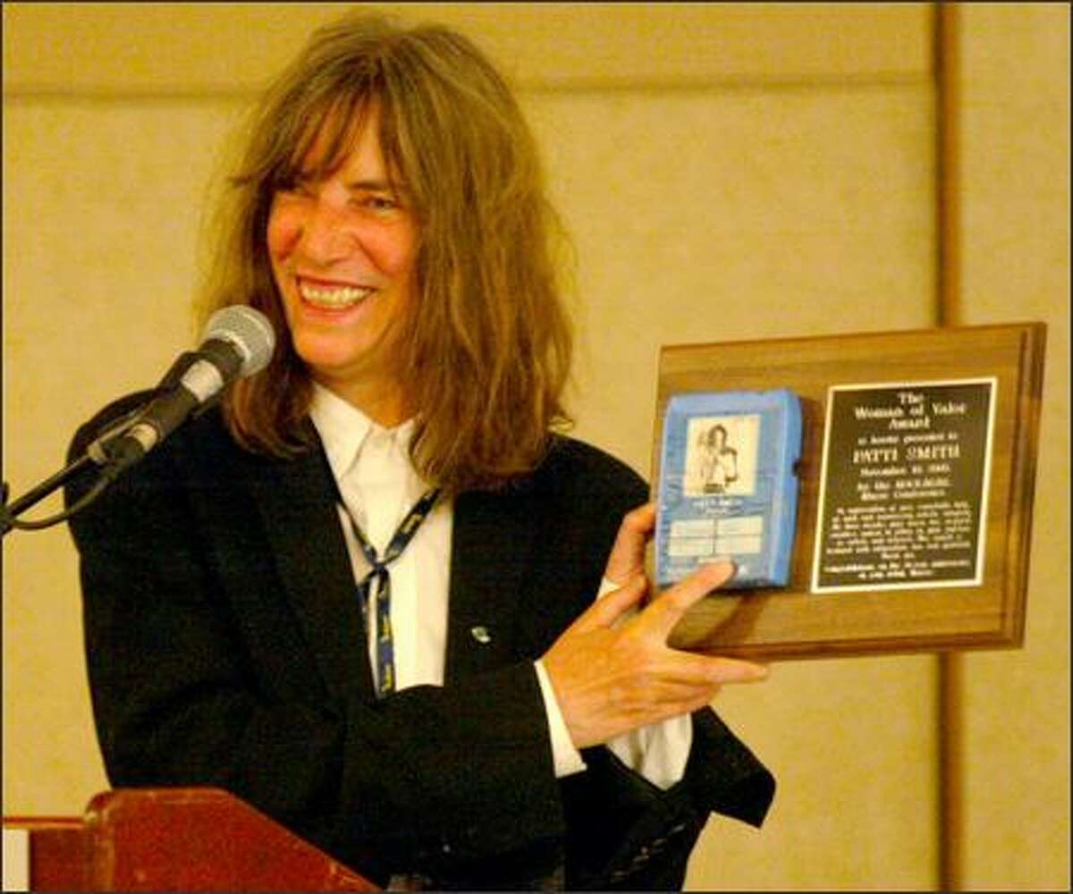 Patti Smith holds up her Woman of Valor Award to the audience. She explained that her father bought a cassette with her picture on the label and gave it to her.